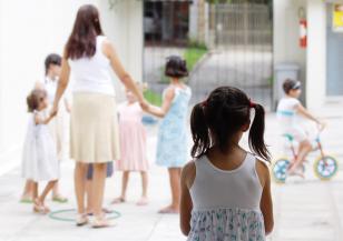 Menina observa outras crianças brincarem